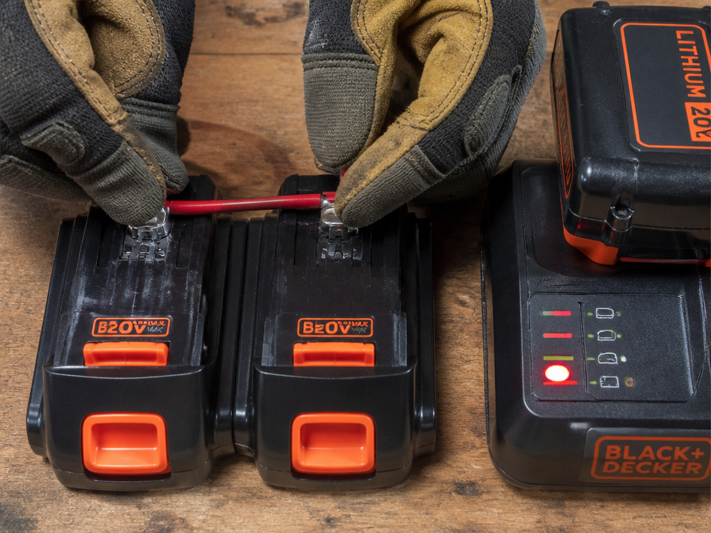 Close-up of jump-starting a Black & Decker drill battery using a second battery and wire.