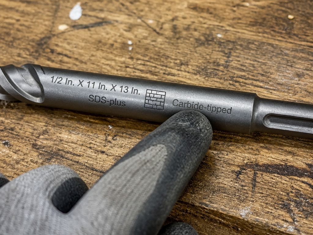 Close-up of engraved markings and specifications on a masonry drill bit.