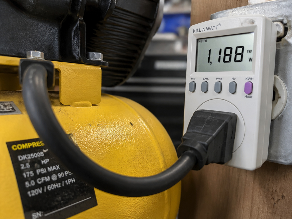 Digital wattmeter measuring air compressor electrical usage in watts.