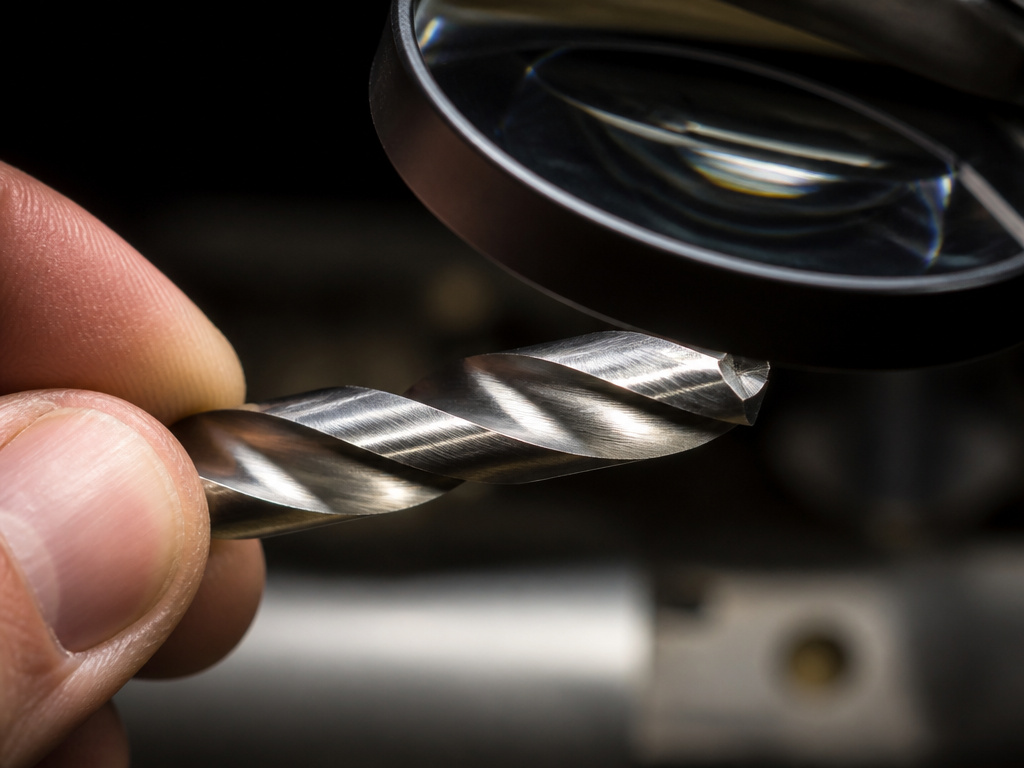 Close-up inspection of a drill bit's cutting edges and flutes for rust damage.
