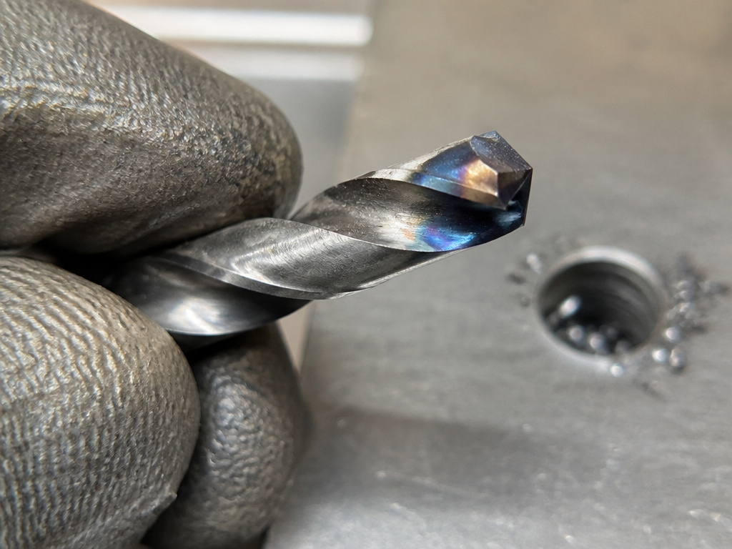 Close-up inspection of a discolored, overheated drill bit for stainless steel.